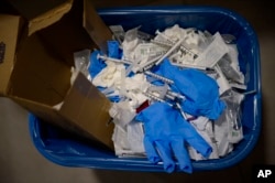 FILE - a view of a waste basket with syringes and gloves after residents received a dose of the third Pfizer COVID-19 vaccine