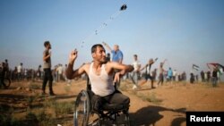 Seorang pria Palestina dari kursi rodanya melempar batu ke arah pasukan Israel, dalam aksi protes menuntut hak untuk kembali tinggal di kampung halaman, dalam aksi di perbatasan Gaza-Israel (foto: ilustrasi). 