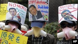 Protesters hold placards condemning the use of nuclear power at a rally in Tokyo, Sunday, April 10, 2011, after a devastating earthquake and tsunami crippled the Fukushima Daiichi nuclear complex in northeastern Japan last month