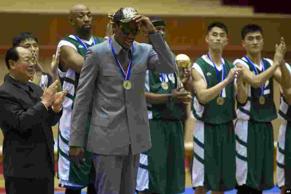 Dennis Rodman levanta o chapéu enquanto jogadores americanos e norte-coreanos aplaudem no final do jogo de basquetebol em Pyongyang, Jan. 8, 2014.
