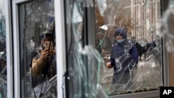 A man takes a photo of windows of a police kiosk damaged by demonstrators during a protest in Almaty, Kazakhstan, Jan. 5, 2022. 