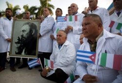 Cuban doctors and medical professionals who will depart for Italy to assist with the pandemic in the country pose for photographers with a photo of Fidel Castro and flags of Italy and Cuba, in Havana, Cuba, March 21, 2020.