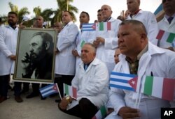 Cuban doctors and medical professionals who will depart for Italy to assist with the pandemic in the country pose for photographers with a photo of Fidel Castro and flags of Italy and Cuba, in Havana, Cuba, March 21, 2020.