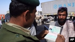 FILE - A Pakistani border guard checks the passport of an Afghan national entering Pakistan through the Chaman post at Pakistan-Afghanistan border.