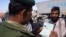 FILE - A Pakistani border guard checks the passport of an Afghan national entering Pakistan through the Chaman post at Pakistan-Afghanistan border.