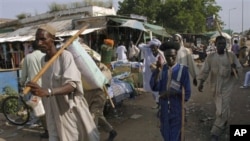 In this Friday, Sept. 16, 2011 photo, men walk through the a market in Damazin, the regional capital of the Blue Nile region, south east of Khartoum, Sudan. The area has been the site of clashes between government troops from Sudan's Arab north and black 