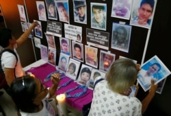 FILE - Families of victims of alleged extra-judicial killings in the so-called "war on drugs" remove portraits of their slain relatives, July 9, 2019, in Manila, Philippines.