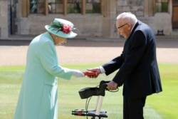 FILE - Captain Sir Thomas Moore receives his knighthood from Britain's Queen Elizabeth, during a ceremony at Windsor Castle in Windsor, England, July 17, 2020.