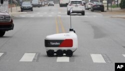 A food delivery robot crosses a street in Ann Arbor, Mich. on Thursday, Oct. 7, 2021. (AP Photo/Carlos Osorio)