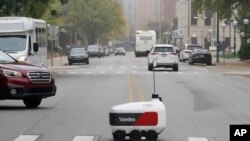 A food delivery robot crosses a street in Ann Arbor, Mich. on Thursday, Oct. 7, 2021. (AP Photo/Carlos Osorio)