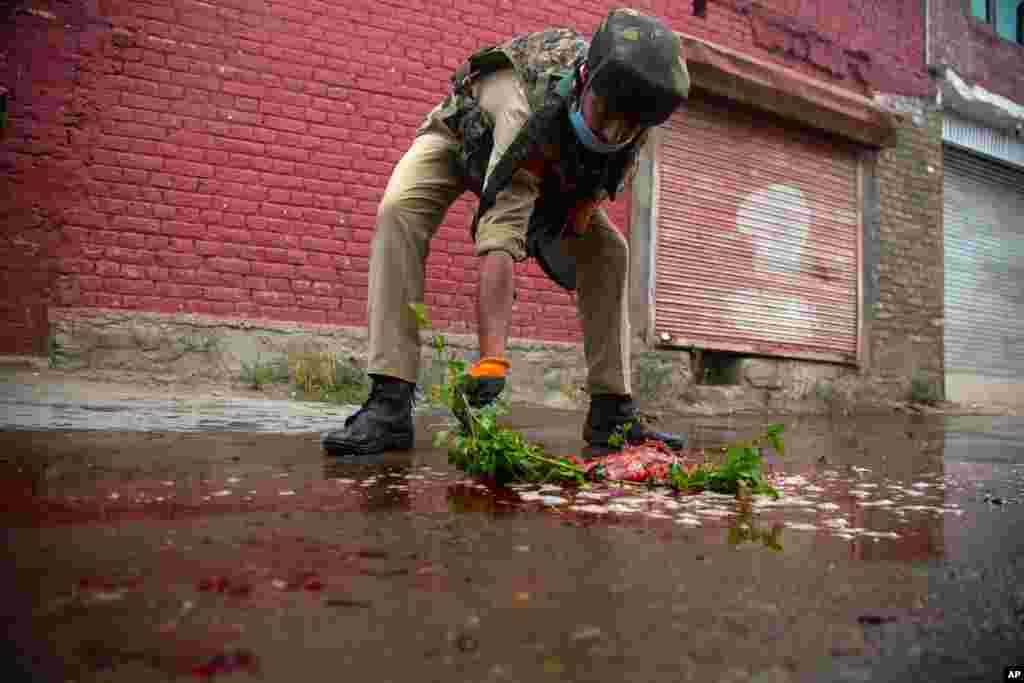 An Indian policeman cleans blood splattered on a street with a tree twig after suspected rebels attack on policemen on the outskirts of Srinagar, Indian-controlled Kashmir.