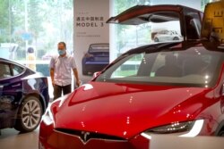 FILE - A customer looks at automobiles in a Tesla car showroom in Beijing, June 11, 2020.
