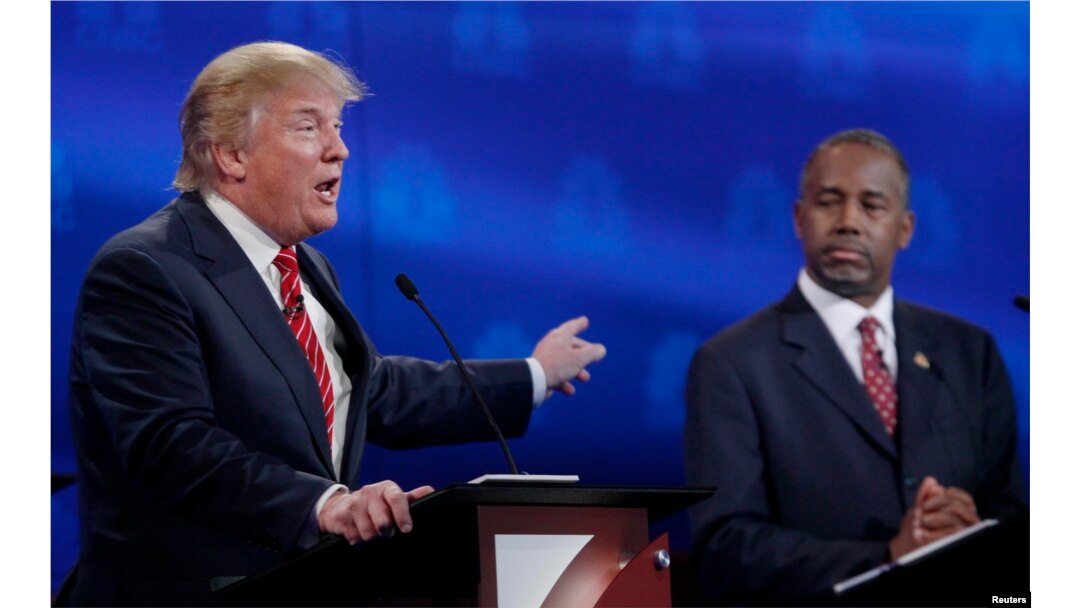 U.S. presidential candidate and businessman Donald Trump, left, speaks as Ben Carson, a retired neurosurgeon, listens at the 2016 U.S. Republican presidential candidates debate held by CNBC in Boulder, Colo., Oct. 28, 2015.