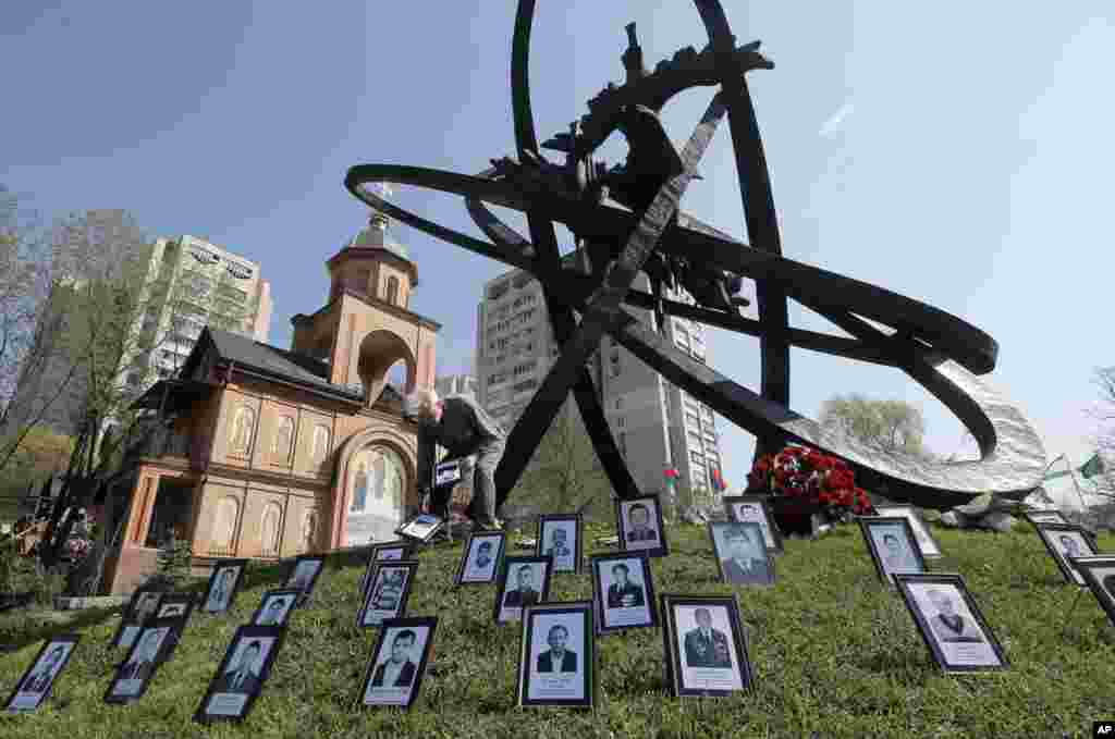 A relative of a Chernobyl victim places a photo near the monument erected in memory of the victims of the Chernobyl explosion in Ukraine&#39;s capital Kyiv, Ukraine.