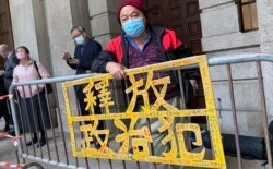 社民连成员曾健成手持标语在终审法院外排队，打算进入内庭旁听支持黎智英 （美国之音/汤惠芸）