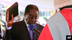 Zimbabwean President Robert Mugabe holds the bible during his inauguration in Harare, August 22, 2013. - AP