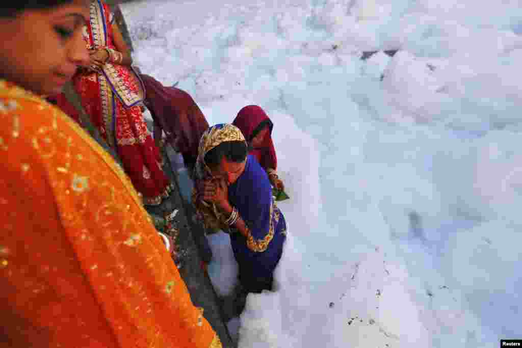 Hindu women worship the sun god Surya in the polluted waters of Yamuna river during the Hindu religious festival of Chatt Puja in New Delhi, India.