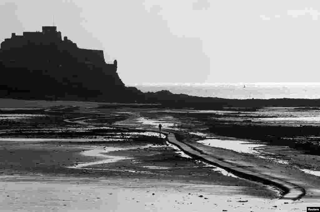 A man walks out on the tidal causeway to Elizabeth Castle in St. Helier, Jersey, Britain.