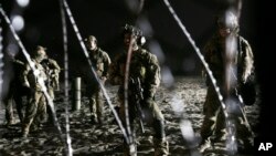 U.S. Border Patrol agents stand on the U.S. side of the border, seen through the concertina wire where the border meets the Pacific Ocean, Thursday, Nov. 15, 2018, from Tijuana, Mexico.