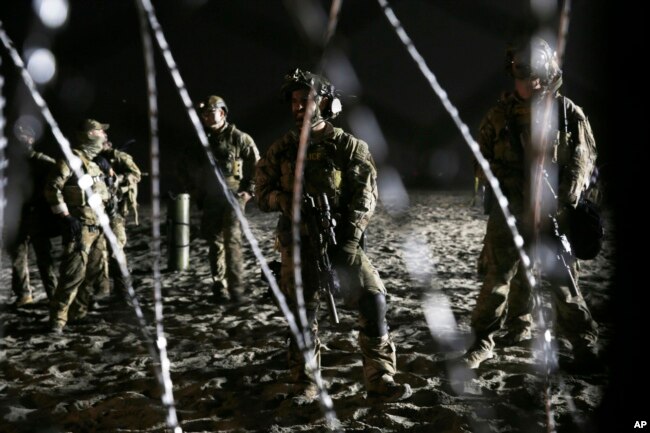 U.S. Border Patrol agents stand on the U.S. side of the border, seen through the concertina wire where the border meets the Pacific Ocean, Thursday, Nov. 15, 2018, from Tijuana, Mexico.