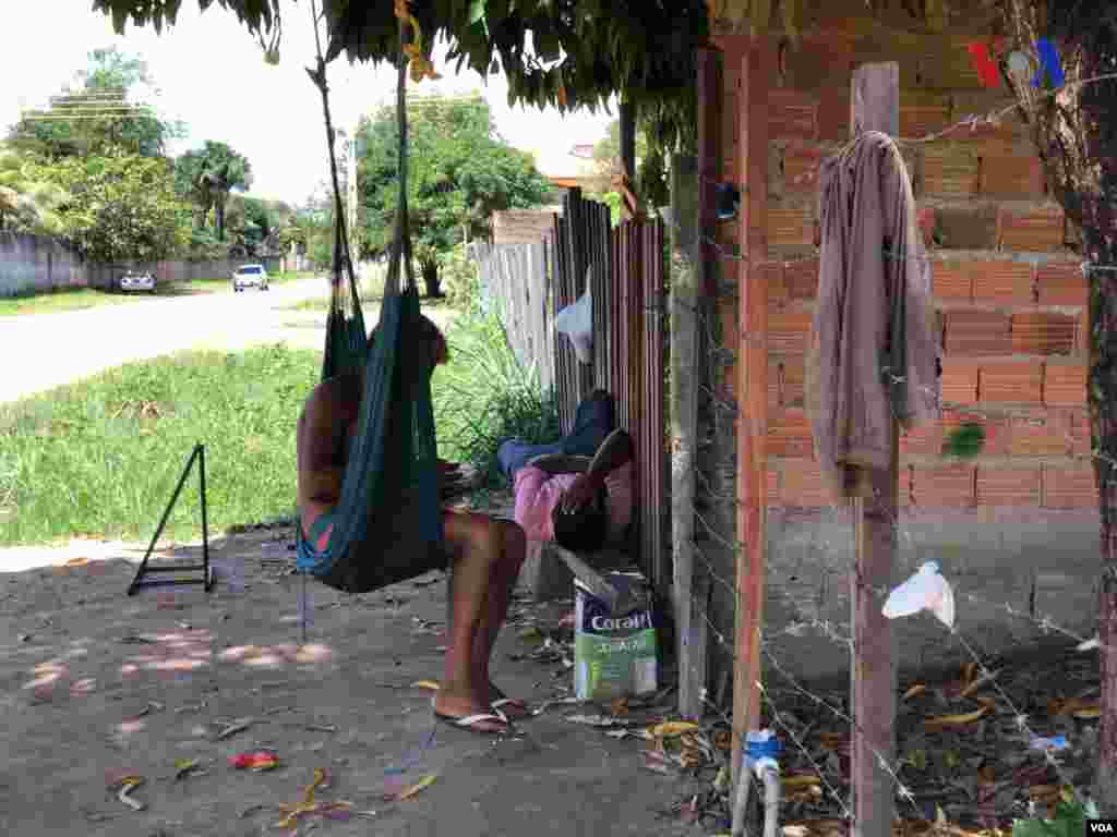 Dos hombre pasan el rato a las afuera del refugio improvisado&nbsp;creado por venezolanos en el vecindario Jardim Floresta, fronterizo de Brasil. Foto: Celia Mendoza - VOA