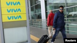 Un hombre camina cerca de un cartel de la aerolínea Viva Air, luego de que la aerolínea cancelara todos sus vuelos debido a las dificultades financieras que enfrenta para operar en el Aeropuerto El Dorado, en Bogotá, Colombia, el 28 de febrero de 2023.