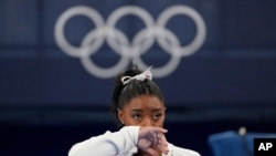 Simone Biles, of the United States, watches gymnasts perform at the 2020 Summer Olympics, July 27, 2021, in Tokyo. 