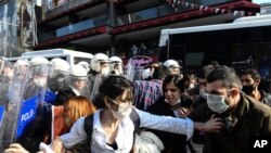 Turkish police officers, in riot gear, and wearing face masks for protections against the spread of the coronavirus, scuffle with protesters during a demonstration in Istanbul, June 2, 2020, against the recent killing of George Floyd in Minneapolis. 