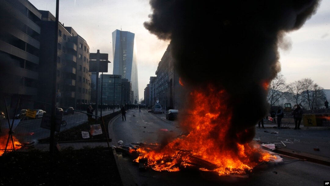 Smoke billows over burning barricades in front of the new ECB headquarters in Frankfurt, Germany, Wednesday, March 18, 2015.
