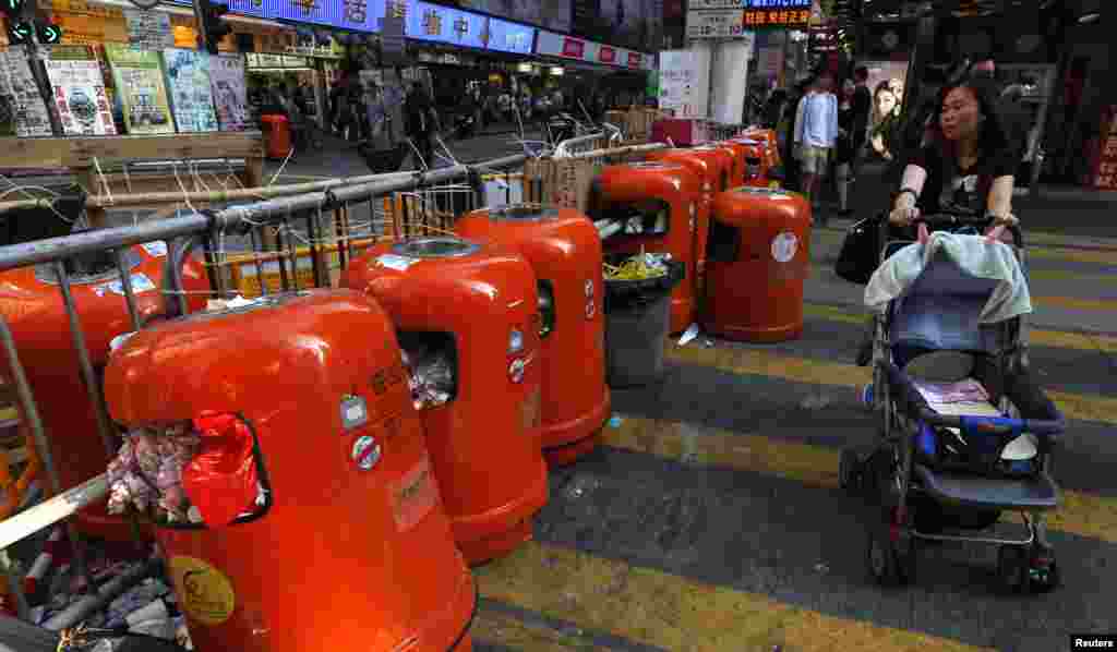 A passerby walks past a barricade with rubbish bins set up by pro-democracy protesters on a side street at Mongkok shopping district in Hong Kong, Oct. 20, 2014. 