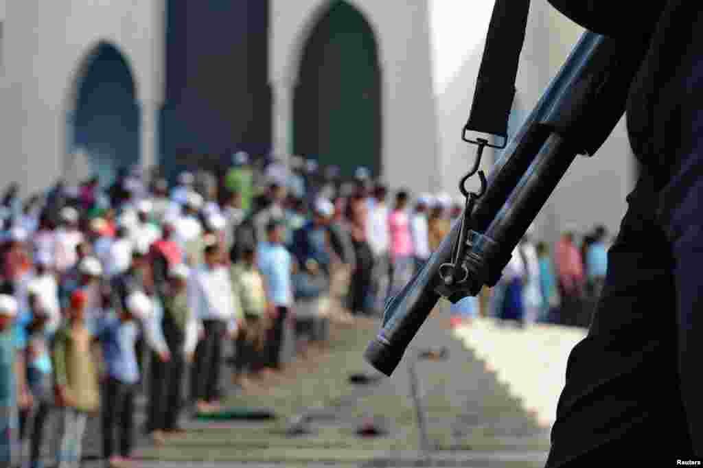 People take part in Friday prayers as members of the police stand guard in Dhaka, Bangladesh. The country is set to vote in nationwide polls on Sunday.