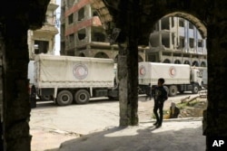 This photo released by the Syrian Arab Red Crescent, show Syrian Red Crescent trucks carrying humanitarian aid to be distributed in Douma, eastern Ghouta, a suburb of Damascus, March 15, 2018.