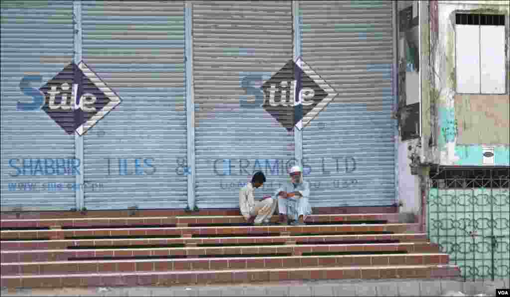 نارتھ کراچی میں بند دکانوں کے باہر یومیہ مزدور وقت گزاری کی غرض سے باتوں میں مشغول ہیں _10