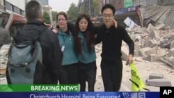 People walk past rubble as they help the injured evacuate after an earthquake in Christchurch, New Zealand, in this February 22, 2011 image taken from video footage.