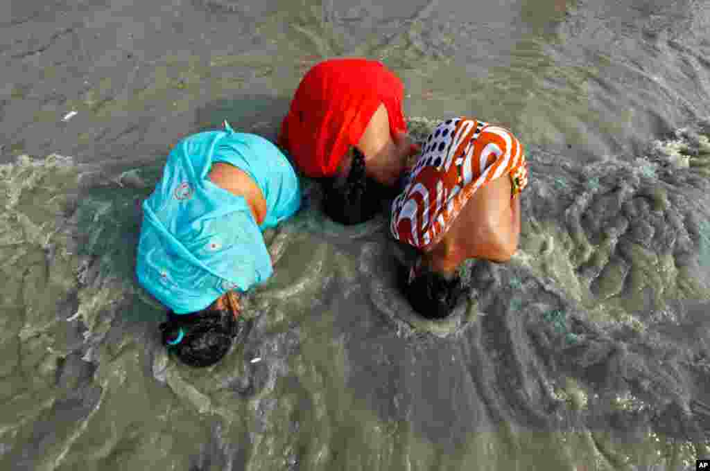 Female Hindu pilgrims take a dip at the confluence of the Ganges river and the Bay of Bengal at Sagar Island, India January 13, 2012. (Reuters)