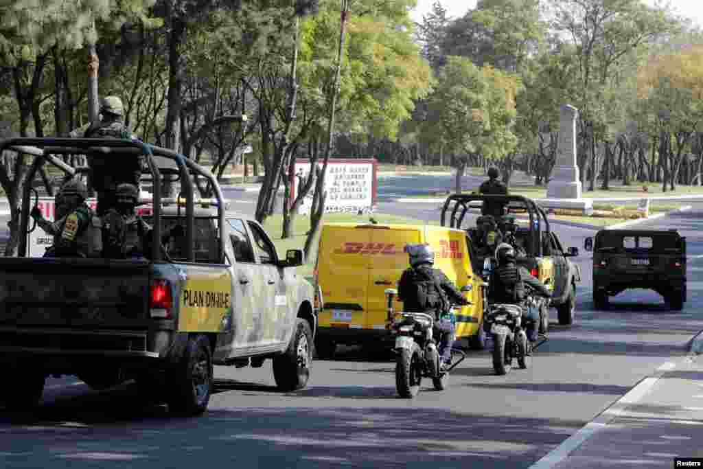 Soldiers and police officers escort a delivery van transporting the first batch of the Pfizer-BioNTech COVID-19 vaccine at the Military College in Mexico City, Mexico.