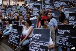 FILE - Anti-government demonstrators hold the names of people killed during months of deadly protests, gathering at a Caracas park Aug. 30, 2017. More than 120 people died in the protests.
