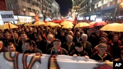 Protesters carrying umbrellas in colors of the national flag march through a street in Skopje, Macedonia, March 10, 2017. Thousands of Macedonians have been protesting against the designation of Albanian as a second official language nationwide.