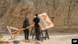 Production crews remove a sign after dangerously high winds forced President Joe Biden to cancel a trip Jan. 7, 2025, to the Eastern Coachella Valley, California, where he was to announce the creation of two new national monuments in California.