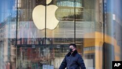A man wears a face mask as he walks past an Apple store that is temporarily closed due to health concerns in Beijing, Tuesday, Feb. 4, 2020. Apple announced that it will temporarily close all of its stores in China due to a virus outbreak. (AP Photo/Mark