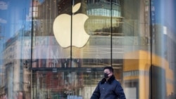 A man wears a face mask as he walks past an Apple store that is temporarily closed due to health concerns in Beijing, Tuesday, Feb. 4, 2020. Apple announced that it will temporarily close all of its stores in China due to a virus outbreak. (AP Photo/Mark