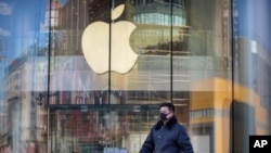 A man wears a face mask as he walks past an Apple store that is temporarily closed due to health concerns in Beijing, Tuesday, Feb. 4, 2020. Apple announced that it will temporarily close all of its stores in China due to a virus outbreak. (AP Photo/Mark