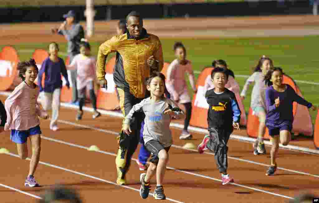 Peraih medali emas olimpiade Usain Bolt dari Jamaika &quot;berkompetisi&quot; dengan anak-anak dalam acara &quot;Klinik Atletik&quot; di Stadion Nasional di Tokyo, Jepang. 