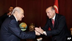 FILE - Turkey's President Recep Tayyip Erdogan, right, shake hands with Devlet Bahceli, the leader of opposition Nationalist Movement Party, at the parliament during its first session in Ankara, Turkey, Oct. 1, 2017.