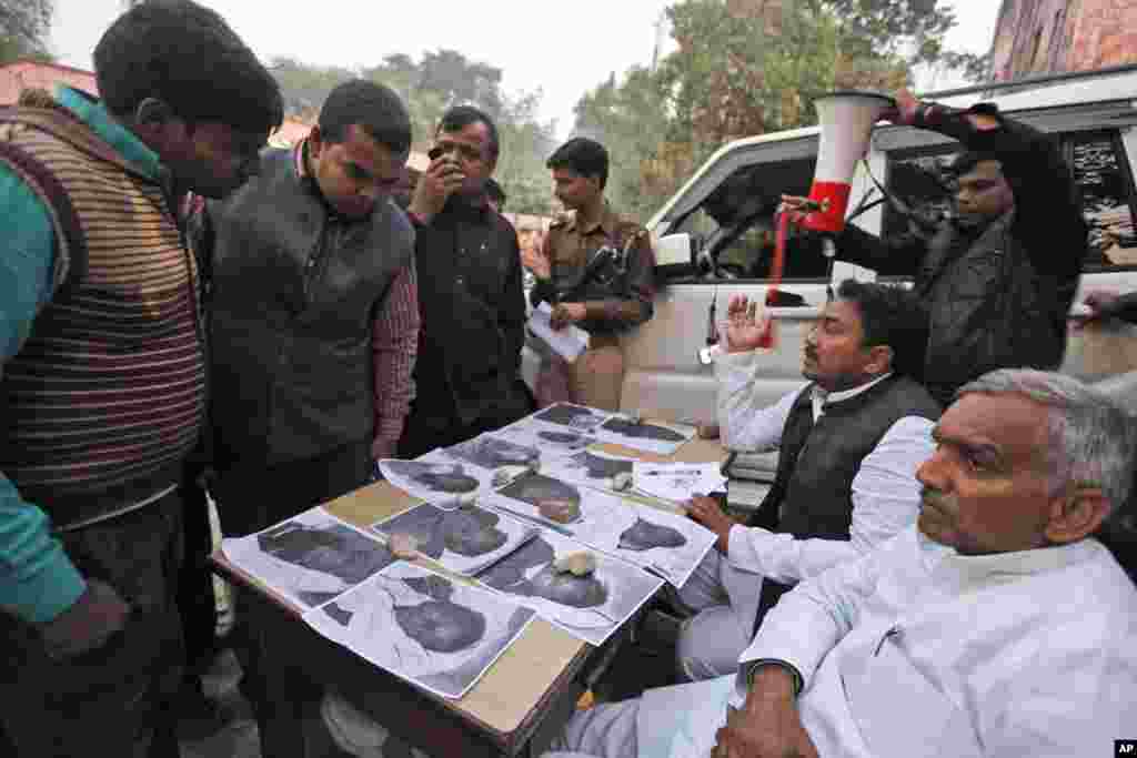 Relatives look at the photos of victims who died in a stampede at a railway station outside a morgue at a hospital, in Allahabad, India, Feb. 11, 2013.