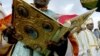 Ethiopian orthodox priests in their satin robes stand under sequinned velvet umbrellas while an other reads from the bible during the annual Epiphany celebrations called "Timket" of the Ethiopian Orthodox Church in Addis Ababa January 20, 2004.