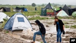 Un couple évacue les inondations dans un camp de réfugiés à Idomeni, en Grèce, le 21 mai 2016.