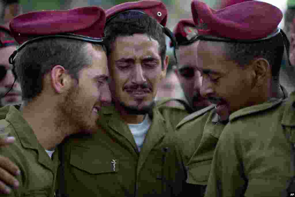 Israeli soldiers of the Paratroopers Brigade mourn over the grave of Sgt. Bnaya Rubel during the funeral at the military cemetery in Holon, Israel, July 20, 2014.