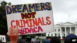 Seorang wanita memegang tanda untuk mendukung program DACA (Deferred Action for Childhood Arrivals), saat reformasi imigrasi di Gedung Putih, Washington, 15 Agustus 2017. (AP Photo/Jacquelyn Martin, File).