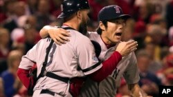 El lanzador relevista Koji Uehara es abrazado por su cátcher, David Ross, luego de que los Medias Rojas ganaran el quinto juego de la Serie Mundial de béisbol.